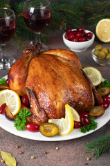 Christmas baked chicken with plum, dogwood, lemon and parsley on brown background