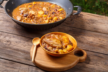 Cheolnt in a large frying pan and a plate on a wooden board on the table.