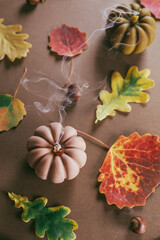 Turned off candles. Wax candles and autumn fall leaves on broun background. Cozy home decor concept.