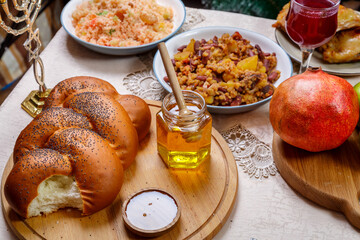 Festive table Rosh hashanah challah honey apples traditional food and burning candles.