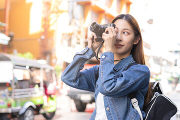 Traveler on vacation weekend, holiday in summer, smile pretty asian young traveling woman backpacker with camera travel photo of photographer in Khao San Road, Street outdoor market, city in Bangkok.
