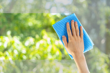 hand with cleaning cloth wash window in room