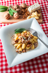 Piatto di deliziosi gnocchi di patate conditi con gorgonzola e noci, pasta italiana 