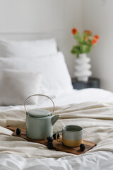 Fototapeta na wymiar Kettle, cup and berries on wooden tray in bed