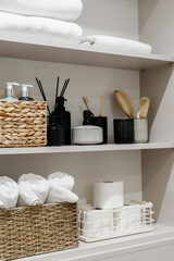Fototapeta na wymiar Cosmetics, towels and toothbrushes in open shelf case at bathroom