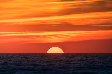 Bright sun setting above dark sea
