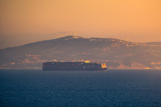 Sailing cargo ship in sea at sunset
