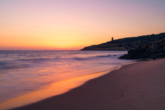 Scenic sunset sky over wavy sea with sandy coast