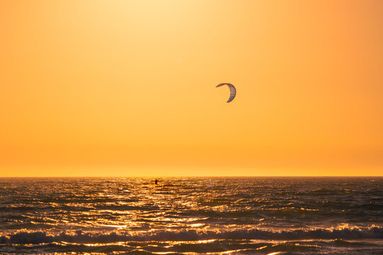 Kite surfer on rippling sea water in sunset