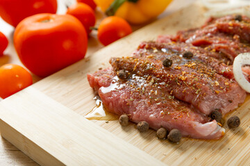 Fresh raw beef steaks with onions and peppers on a cutting board.Fresh vegetables in the background.Meat marinade. Roast beef.
