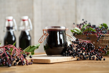 A jar of black elder syrup with fresh Sambucus nigra berries - obrazy, fototapety, plakaty