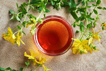 Red oil made from St. John's wort flowers in a bowl on a table