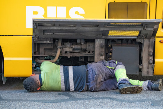 Machanic Working On A Broken Down Bus With Engine Visible