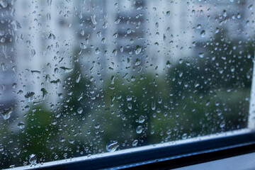 Drops on glass with a blurred city background in the background, drops on a double-glazed window, selective focus