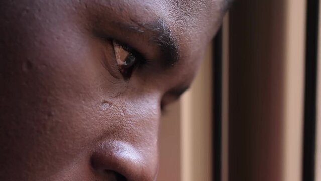 Young sad and depressed black man looking out window