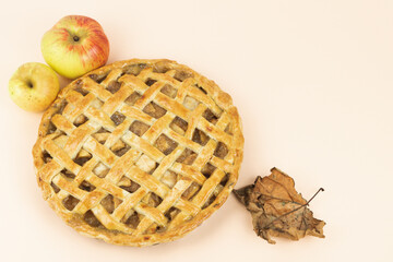 Baked apple pie with trellis decoration. Apples and dried leaves. Copy space.