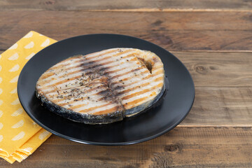 Grilled tuna slice on a wooden plate. Copy space. Top view. Thunnus.