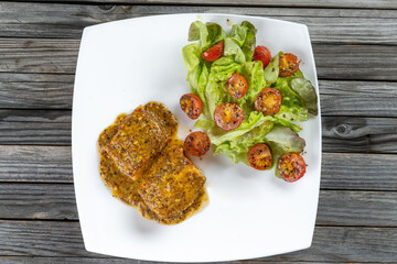 Baked dijon mustard salmon with cherry tomatoes and lettuce in white wine sauce