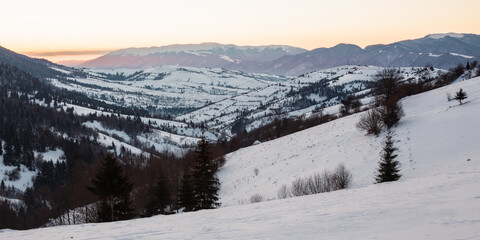 Fototapeta na wymiar carpathian rural landscape in winter. beautiful sunrise in mountains. snow covered hills. scenery with krasna ridge in the distance. synevir village in the valley
