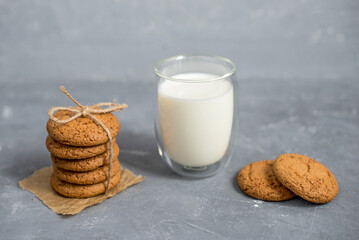 homemade oatmeal cookies on a wooden board in a rustic burlap bag with milk in a transparent glass. The concept of a home bakery, proper and healthy nutrition. Copy space for text