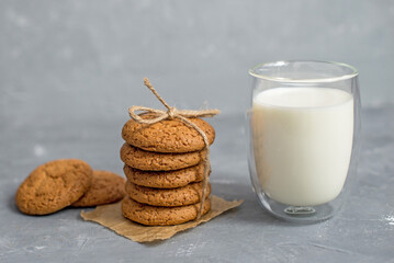 homemade oatmeal cookies on a wooden board in a rustic burlap bag with milk in a transparent glass. The concept of a home bakery, proper and healthy nutrition. Copy space for text