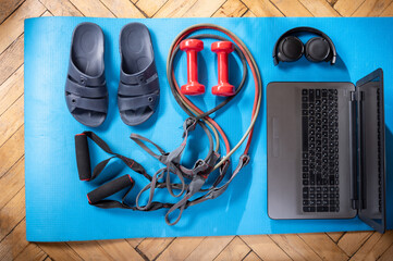 Pool slippers and a laptop. Fitness items and laptop. Rubber expanders and red dumbbells. Dumbbells and laptop.