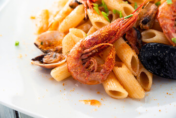 Piatto di deliziose penne rigate condite con frutti di mare e bottarga di muggine, cibo italiano 