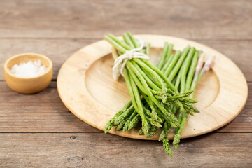 Asparagus is green and straight vegetable. Fresh, green asparagus is crispy for cook on wood table with salt