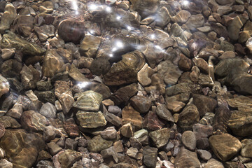 Top view of shining sunlight on Aegean sea and stones.