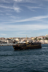 View of a traditional tour boat on Bosphorus in Istanbul. European side is in the view. It is a sunny summer day.