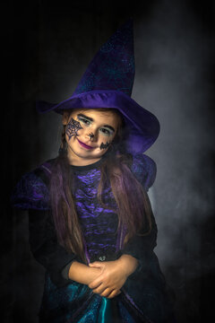 Halloween portrait of a young girl stylised for wicked witch in a purple and black dress