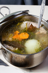 Freshly home made chiken broth in kitchen pan with ladle.