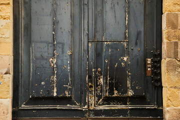 Lucca, Italy - June 6: Worn doors showing much bare wood and ornate hinges.