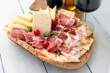 Vassoio con salumi, prosciutti, formaggi e un bicchiere di vino rosso, cibo sardo 