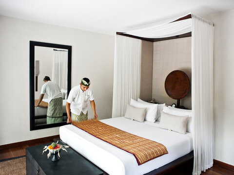 Butler fixes bed in in a privatel villa at a resort. Sanur, Bali, Indonesia.