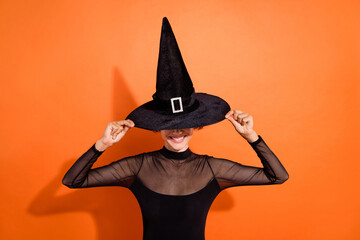 Photo of scary cheerful girl dressed black gothic dress arms headwear smiling orange color background
