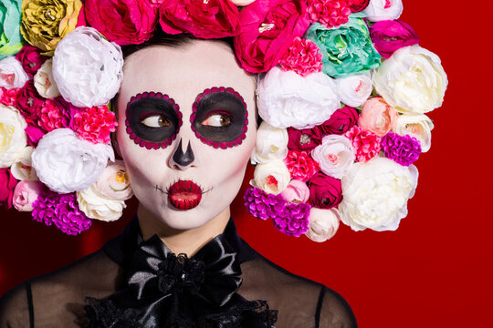 Closeup photo of beautiful skeleton death flirty bride mistress lady death day ritual calaverita facial printing zombie trend send kiss floral headband costume isolated red color background