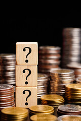 Wooden blocks with question marks with coins stacked, Money Insurance And Tax Question. vertical.                         