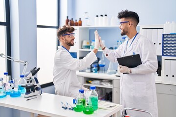 Young couple wearing scientist uniform using touchpad at laboratory