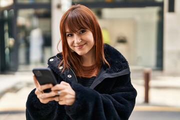 Young woman smiling confident using smartphone at street