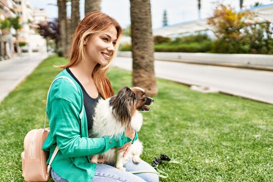Young caucasian girl smiling happy holding dog at the city.