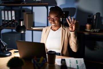 Beautiful black woman working at the office at night showing and pointing up with fingers number...
