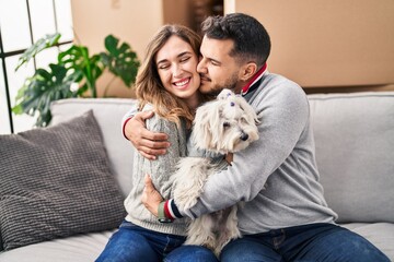 Man and woman smiling confident sitting on sofa with dog at new home