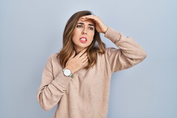 Young woman standing over isolated background touching forehead for illness and fever, flu and cold, virus sick