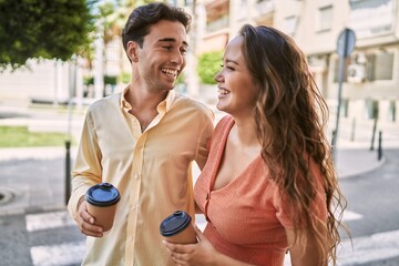 Man and woman couple drinking coffee and hugging each other at street