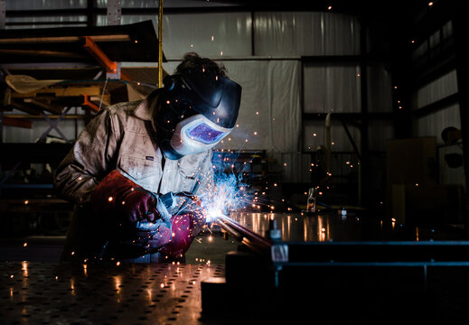 Industrial welder with torch MIG welding metal in a manufacturing factory 