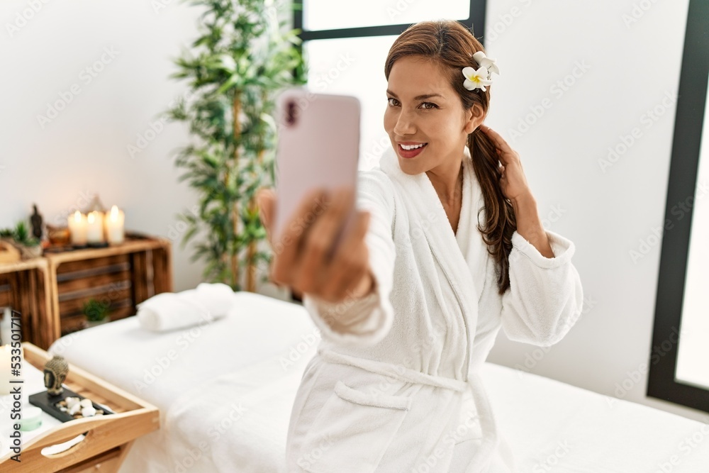 Poster young latin woman wearing bathrobe male selfie by the smartphone