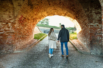 Obraz na płótnie Canvas A portrait of a happy romantic couple walking outdoors in the surroundings of an old fortress