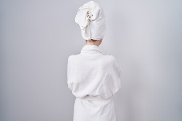 Blonde caucasian woman wearing bathrobe standing backwards looking away with crossed arms - obrazy, fototapety, plakaty