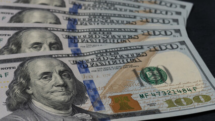billetes de 100 dolares estadounidenses apilados en abanico sobre fondo negro